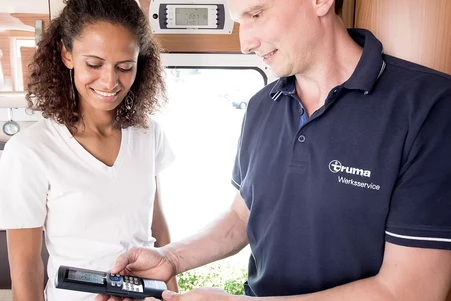 Ein Kundenberater von Truma hilft einer Kundin bei einem Problem mit ihrem Wohnwagen.